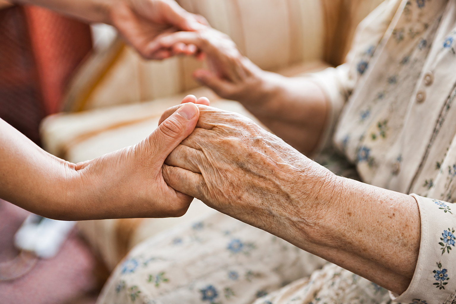Caregiver gently holding an older adult’s hands